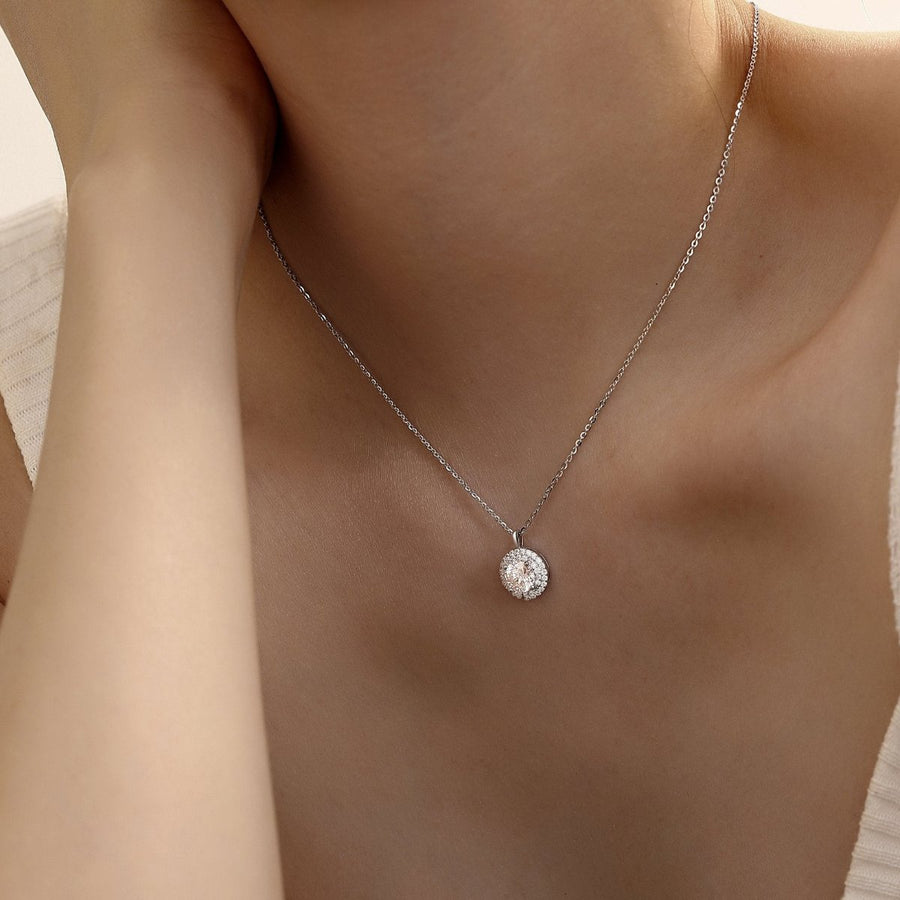 The centerpiece features a 1 carat Moissanite, renowned for its exceptional sparkle and clarity, surrounded by a halo of smaller stones that enhance its radiance. The delicate silver chain complements the pendant perfectly, making it a versatile piece suitable for both everyday wear and special occasions. 