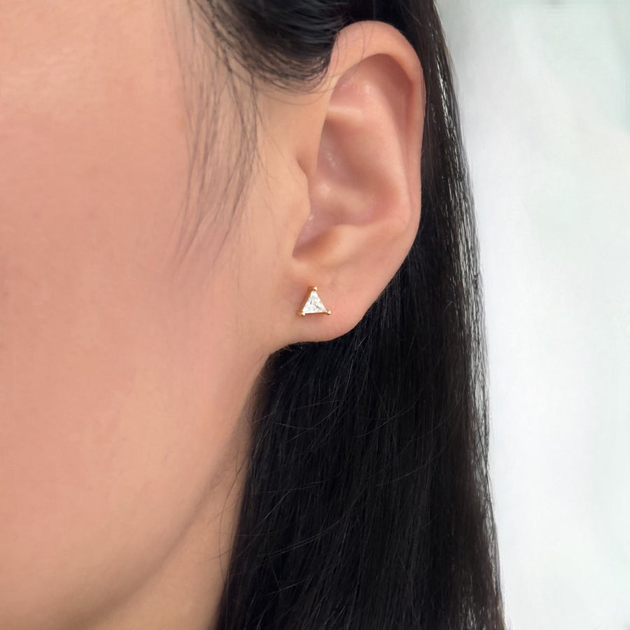 These elegant gold earrings feature a unique design with a triangular cubic zircon at the top and a V-shaped lower part adorned with sparkling cubic zircon, offering a touch of sophistication and glamour to any outfit. The combination of geometric shapes and shimmering accents makes these earrings a stylish and eye-catching accessory for any occasion.