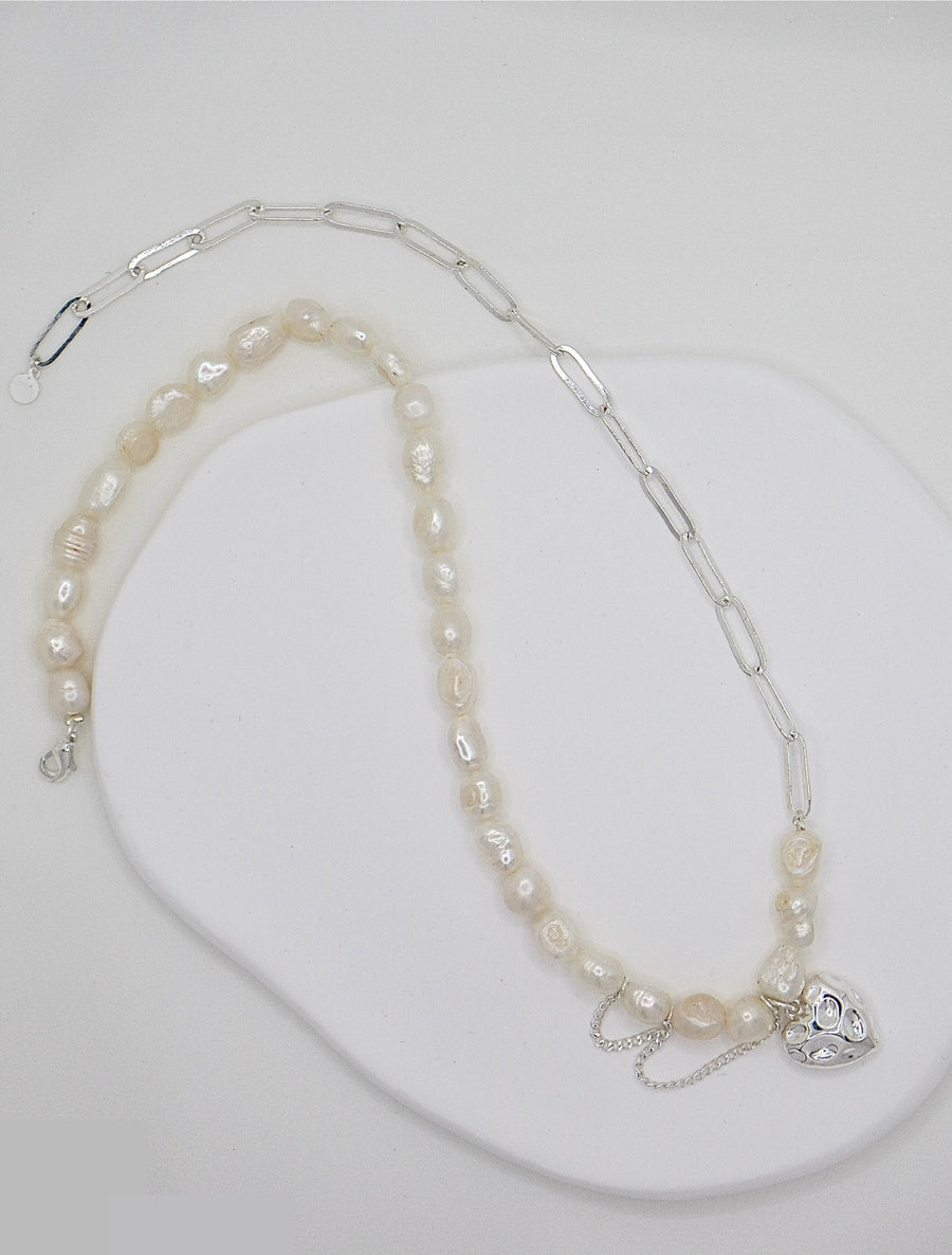 A delicate fusion of classic and contemporary—a freshwater pearl strand meets bold silver links, complete with a charming heart pendant for a touch of romance. 