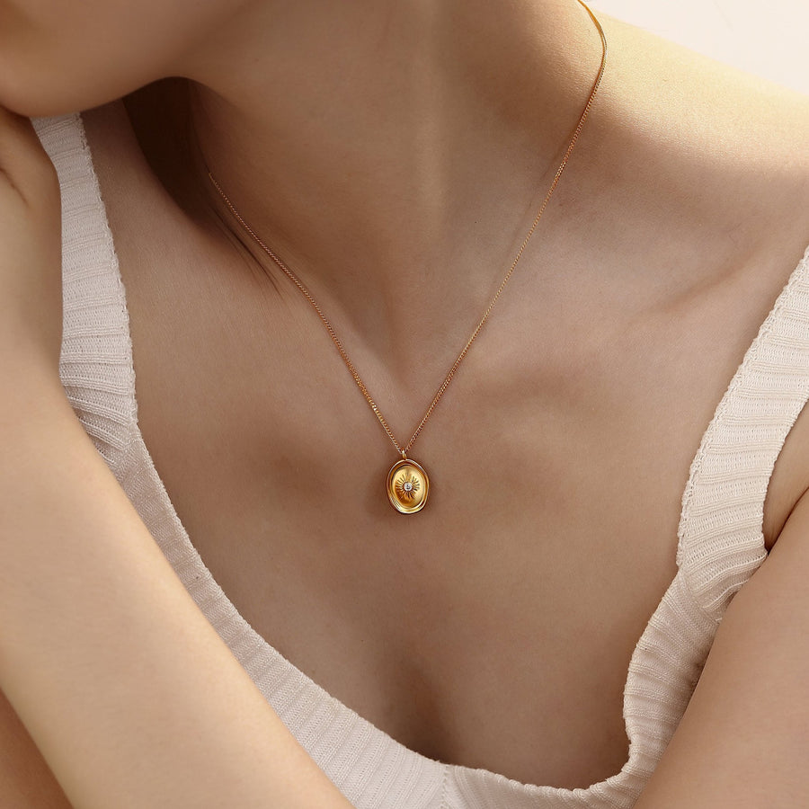 The centerpiece, an oval pendant, showcases a captivating sunburst pattern that emanates from a central clear gemstone, symbolizing clarity and purity. Elevate your style with this timeless accessory that promises enduring beauty and an ethereal glow around your neckline. 