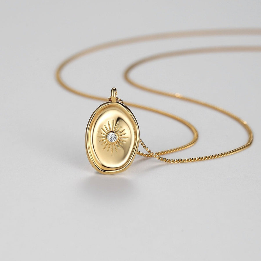 The centerpiece, an oval pendant, showcases a captivating sunburst pattern that emanates from a central clear gemstone, symbolizing clarity and purity. Elevate your style with this timeless accessory that promises enduring beauty and an ethereal glow around your neckline. 