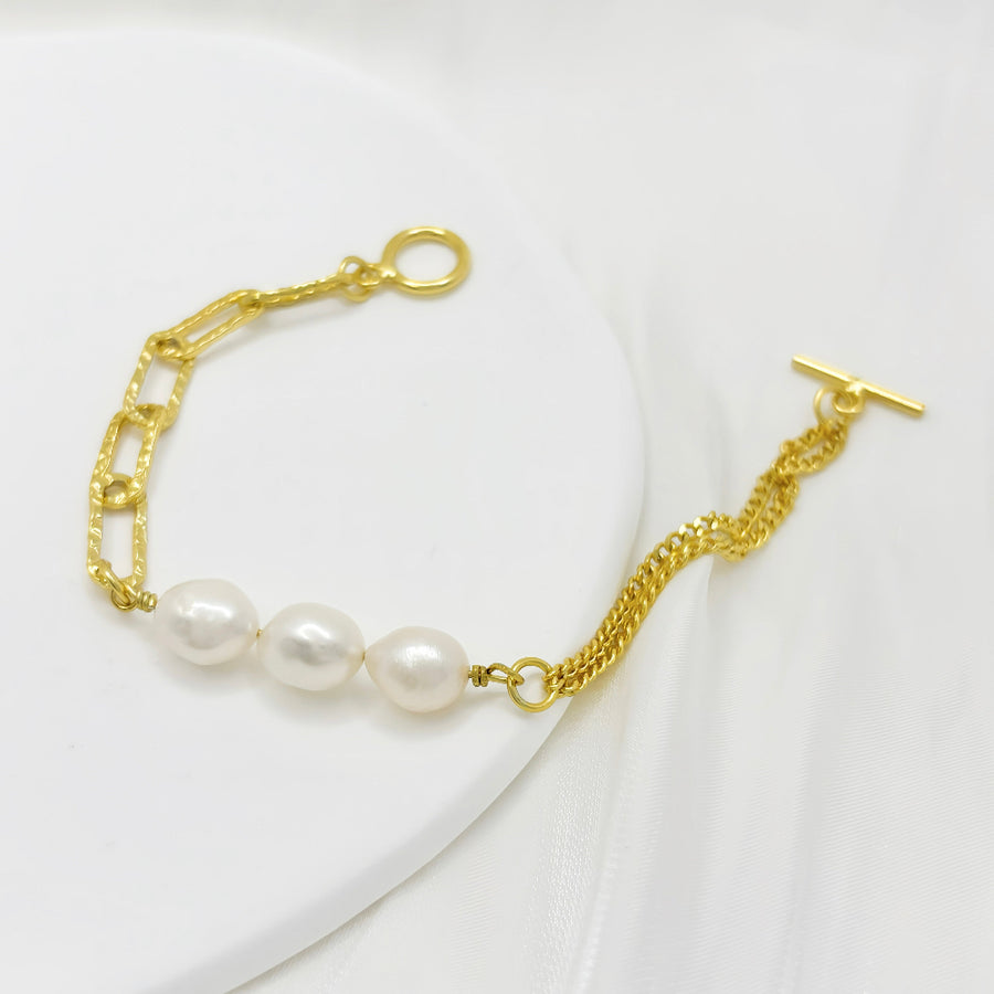 This modern gold vermeil bracelet features a unique combination of bold gold chains and natural baroque pearls, offering a striking contrast of textures. Designed with a toggle clasp for easy wear, this piece adds a statement touch to both casual and formal outfits.