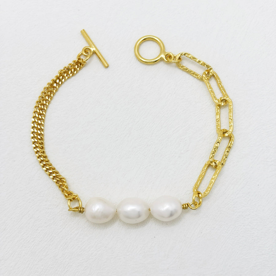 This modern gold vermeil bracelet features a unique combination of bold gold chains and natural baroque pearls, offering a striking contrast of textures. Designed with a toggle clasp for easy wear, this piece adds a statement touch to both casual and formal outfits.