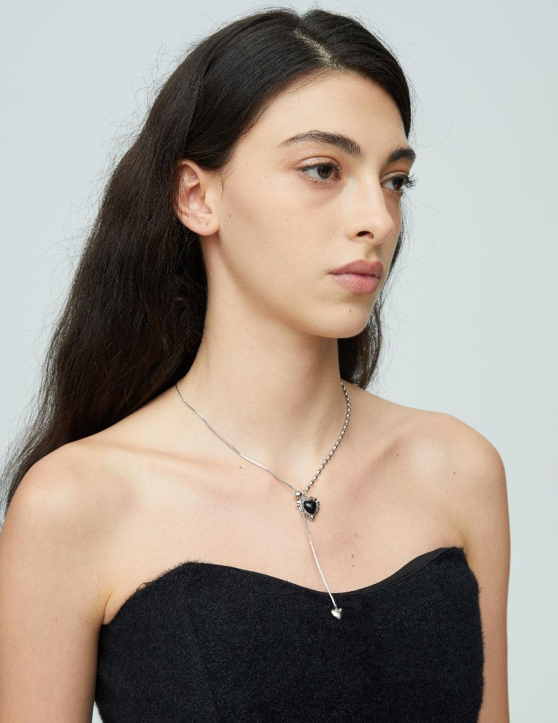 Crafted with precision, it features a stunning artificial agate at its center. The innovative asymmetrical design pairs a classic snake chain on one side with an intricate olive bead chain on the other, creating an alluring contrast that captivates and charms. The adaptability of the design, the adjustable chain in the pendant, ensures your perfect fit for any occasion.