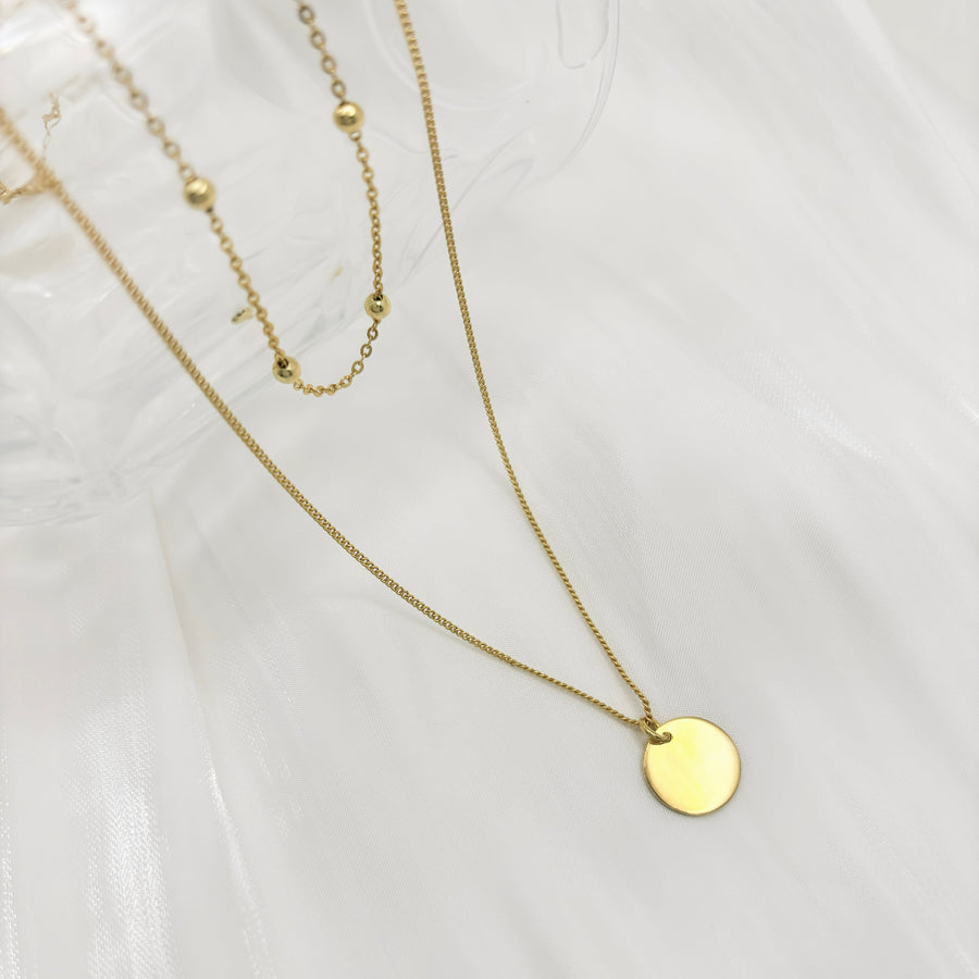 925 Sterling silver necklace. This layered gold necklace combines a sleek coin pendant with delicate bead accents, offering a chic and versatile accessory for any look. Effortlessly elegant, this double-layer design adds depth and charm to your style, perfect for both casual and formal occasions.