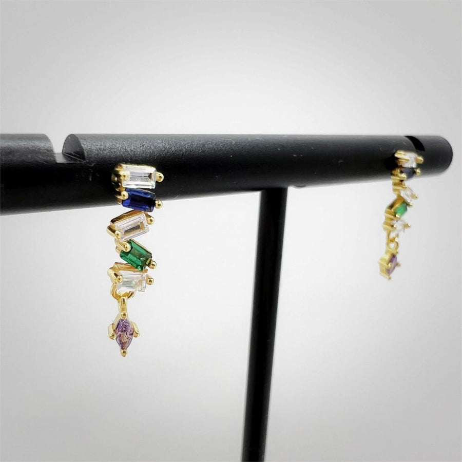These elegant 925 silver earrings feature a vertical arrangement of cubic zircon in a gold setting, showcasing a sequence of blue, green, and clear cubic zircon, with a small purple gem at the bottom. Perfect for adding a touch of sophistication and color to any outfit, these earrings are a must-have for those who love unique and vibrant accessories. 