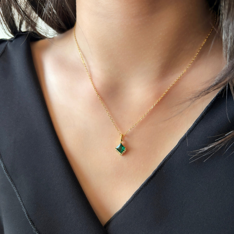 This elegant 925 silver necklace features a delicate gold chain and a striking pendant. The pendant showcases a square-cut green cubic zircon, framed by a border of small, sparkling diamonds cubic zircon, adding a touch of sophistication and luxury to any outfit. Perfect for any occasion, this necklace is a timeless piece that enhances both everyday and special event looks with its vibrant and refined design.