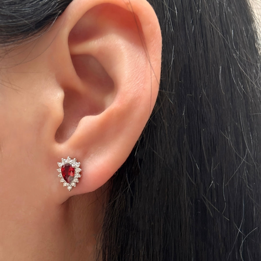 Elevate your elegance with these teardrop-shaped silver stud earrings, showcasing a stunning red cubic zircon encircled by dazzling cubic zircon accents. A timeless design that adds a touch of glamour to any outfit.