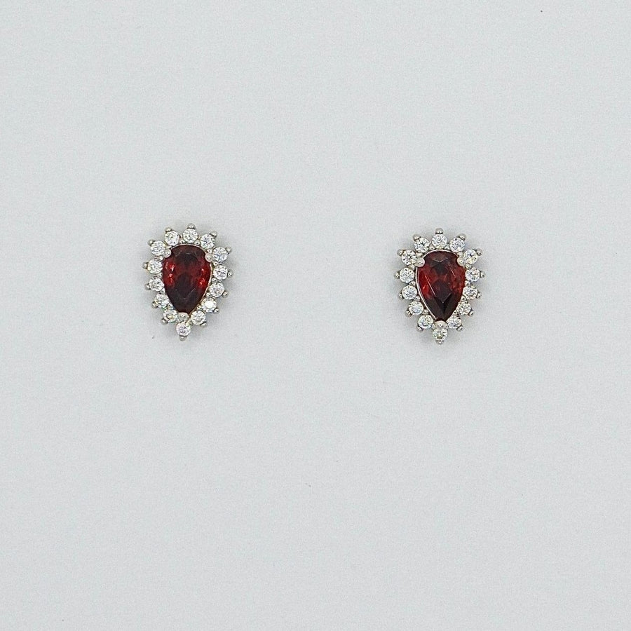 Elevate your elegance with these teardrop-shaped silver stud earrings, showcasing a stunning red cubic zircon encircled by dazzling cubic zircon accents. A timeless design that adds a touch of glamour to any outfit.