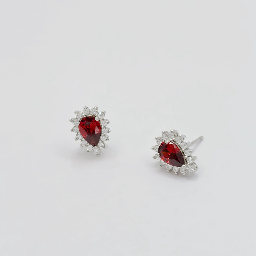 Elevate your elegance with these teardrop-shaped silver stud earrings, showcasing a stunning red cubic zircon encircled by dazzling cubic zircon accents. A timeless design that adds a touch of glamour to any outfit.