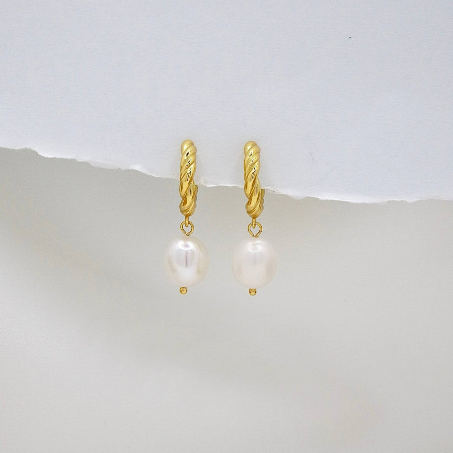 The 925 silver earrings feature a delicate 18K gold-plated twisted hoop paired with an elegant baroque pearl drop. Combining classic charm and contemporary style, these earrings bring sophistication and natural beauty to any look. Perfect for both casual elegance and formal occasions.