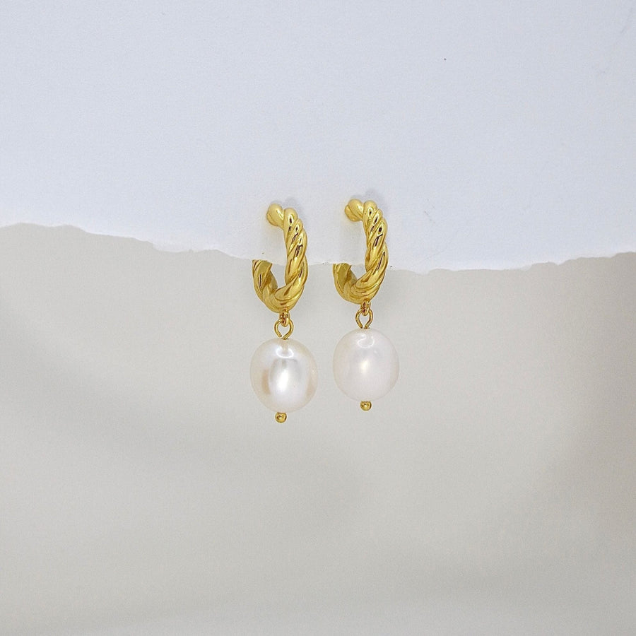 The 925 silver earrings feature a delicate 18K gold-plated twisted hoop paired with an elegant baroque pearl drop. Combining classic charm and contemporary style, these earrings bring sophistication and natural beauty to any look. Perfect for both casual elegance and formal occasions.