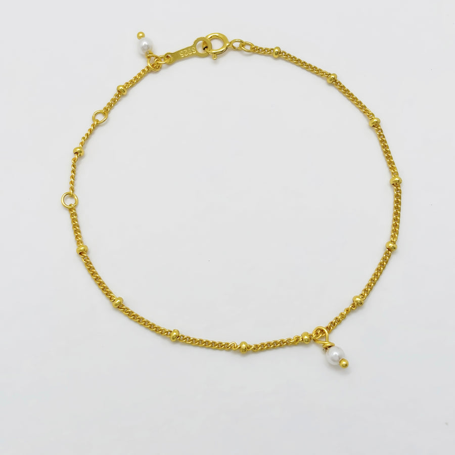 This elegant gold vermeil bracelet features delicate bead details and a charming pearl drop, adding a touch of sophistication to your style. Crafted with precision and adorned with subtle accents, this bracelet is perfect for everyday wear or special occasions.