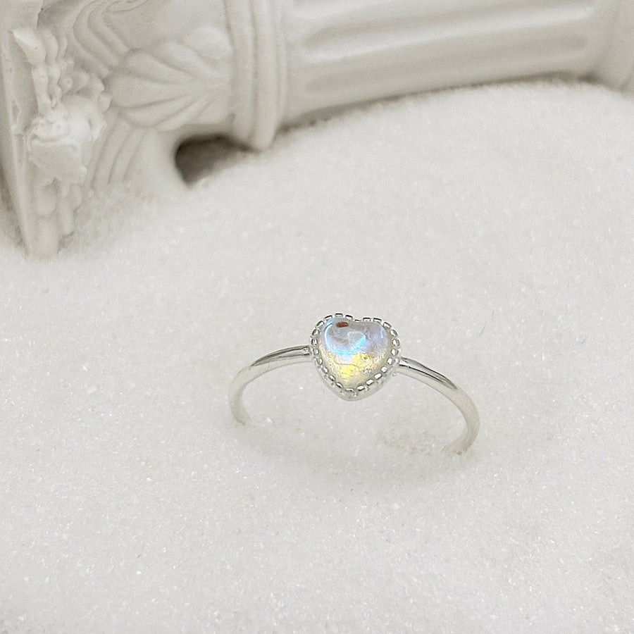 This beautiful ring features a stunning moonstone set in 925 sterling silver. The unique design is sure to catch the eye. The moonstone is heart shaped and has a blue and pink hue that changes with the light, creating a magical effect. 