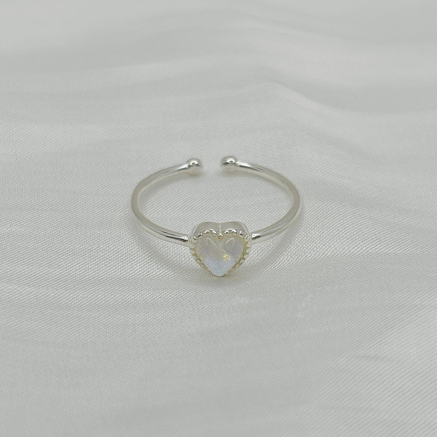 This beautiful ring features a stunning moonstone set in 925 sterling silver. The unique design is sure to catch the eye. The moonstone is heart shaped and has a blue and pink hue that changes with the light, creating a magical effect. 