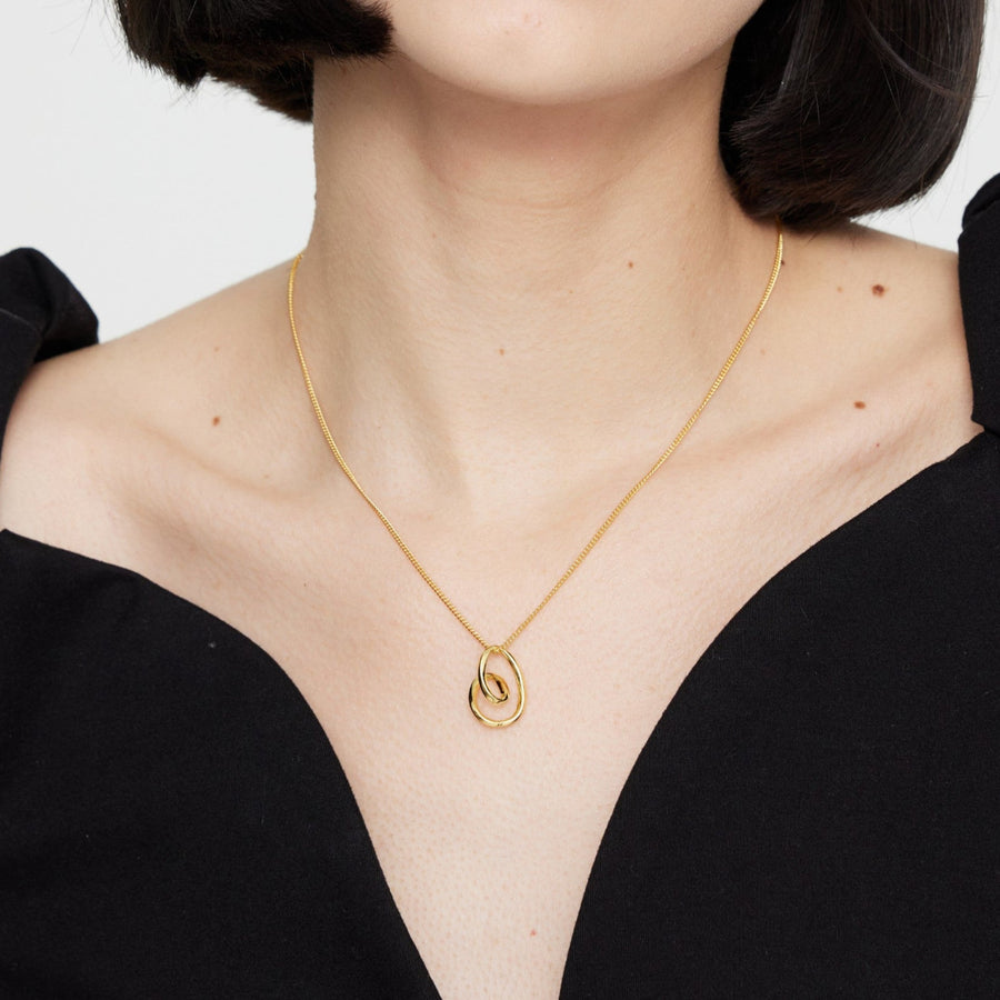 This elegant silver necklace features a delicate gold chain and a unique, abstract heart-shaped pendant. The pendant's fluid, organic design adds a modern twist to a classic symbol of love, making it a perfect accessory for any occasion. 