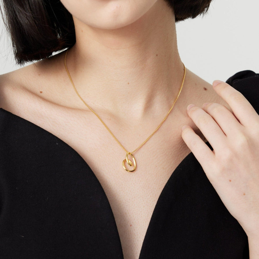 This elegant silver necklace features a delicate gold chain and a unique, abstract heart-shaped pendant. The pendant's fluid, organic design adds a modern twist to a classic symbol of love, making it a perfect accessory for any occasion. 