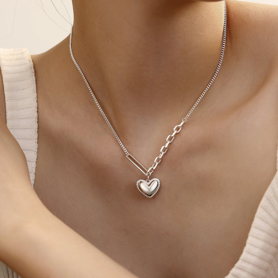 The unique silver asymmetrical chain design sets this piece apart, with one side showcasing a classic, smooth cable chain, and the other side featuring a bold link design. This combination creates a contemporary and eye-catching look that is perfect for any occasion.