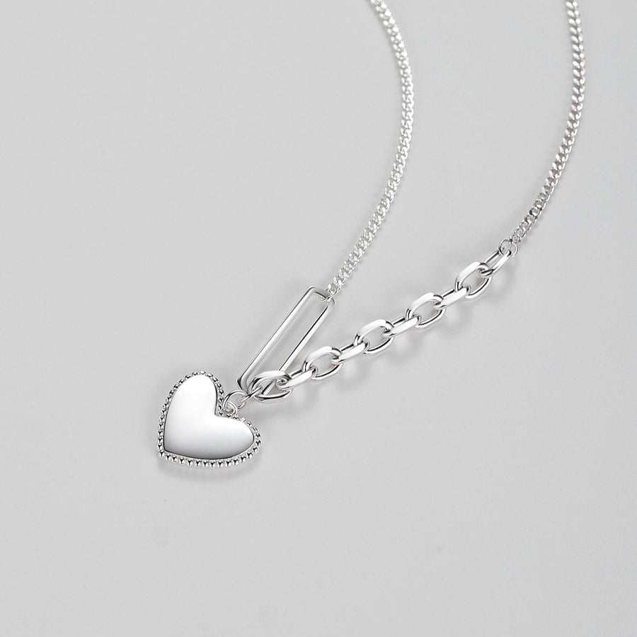 The unique silver asymmetrical chain design sets this piece apart, with one side showcasing a classic, smooth cable chain, and the other side featuring a bold link design. This combination creates a contemporary and eye-catching look that is perfect for any occasion.