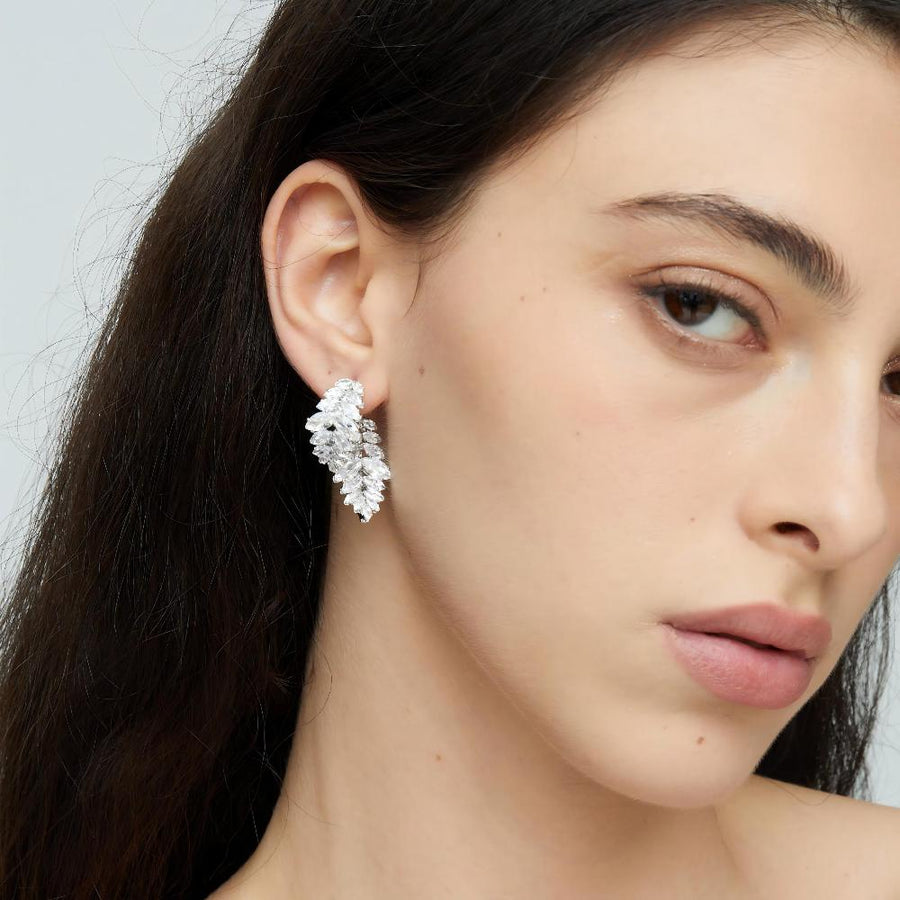 Each earring features a unique design of two overlapping leaf shapes, intricately adorned with sparkling olive-shaped cubic zirconia. Perfect for special occasions or to elevate your everyday style, these earrings are a must-have for anyone who loves detailed and opulent accessories.