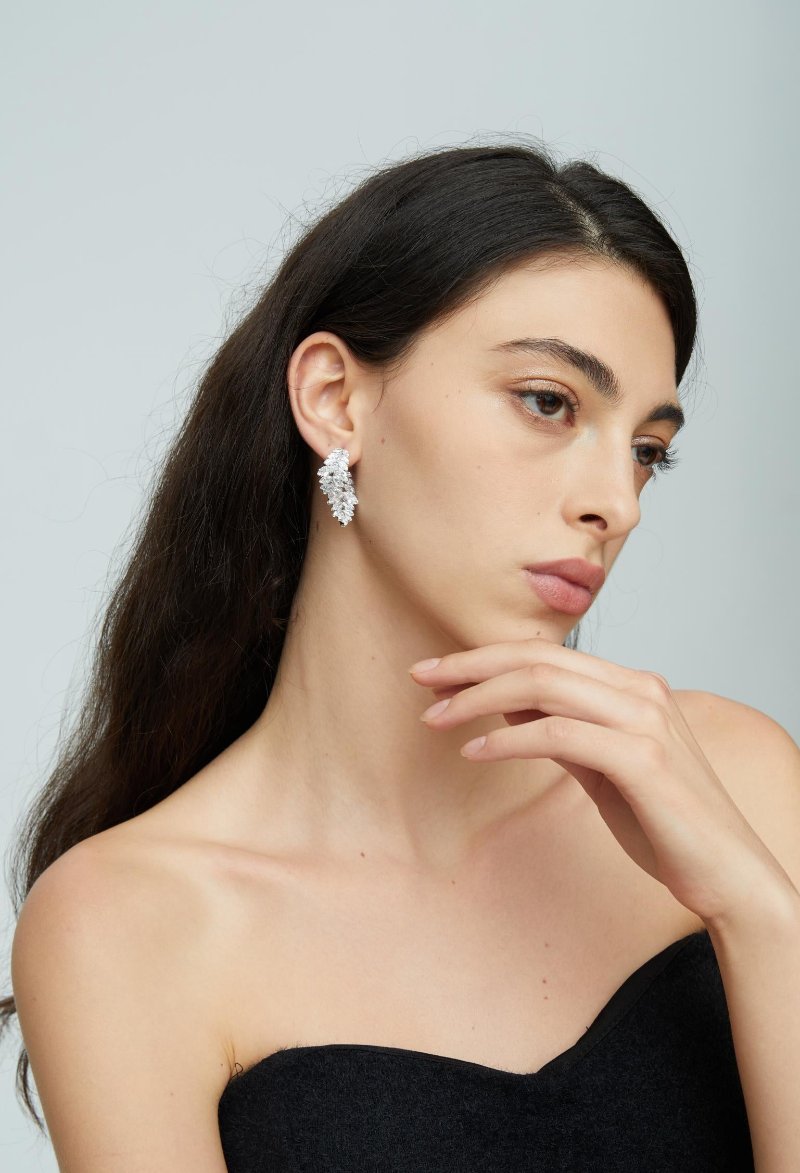 Each earring features a unique design of two overlapping leaf shapes, intricately adorned with sparkling olive-shaped cubic zirconia. Perfect for special occasions or to elevate your everyday style, these earrings are a must-have for anyone who loves detailed and opulent accessories.