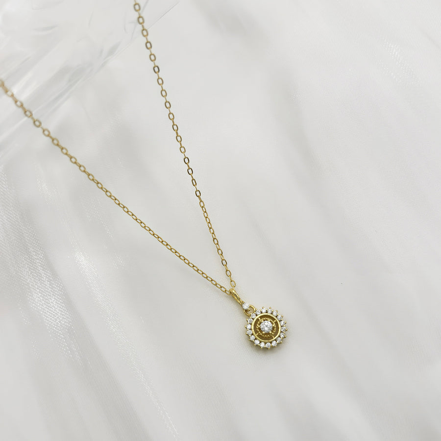 The silver pendant necklace showcases a central zircon stone surrounded by a halo of smaller zircons, creating a radiant and elegant design. Perfect for special occasions or everyday wear, this necklace adds a touch of timeless sophistication to any outfit with its brilliant sparkle.