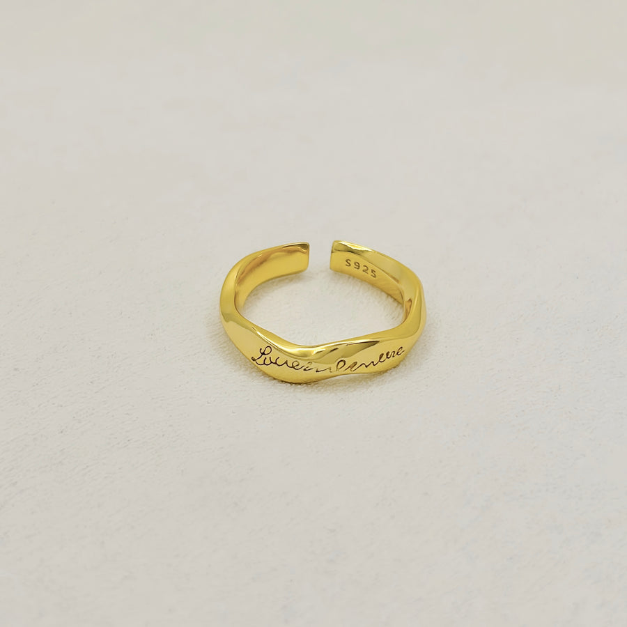 925 silver ring.  A sleek and adjustable gold-tone ring featuring elegant engraved cursive text, perfect for adding a personalized touch to any outfit. Crafted with a modern, twist design, this open-ended ring offers a timeless charm suitable for both casual and formal occasions.