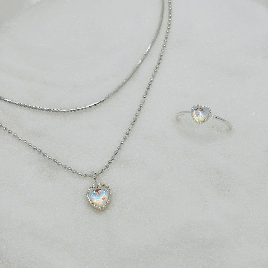 This silver necklace features a stunning moonstone heart-shaped pendant, radiating both beauty and kindness. Its unique design combines beaded and snake chain elements, creating a dual-layered chain for a visually striking effect that exudes a sense of fluidity.