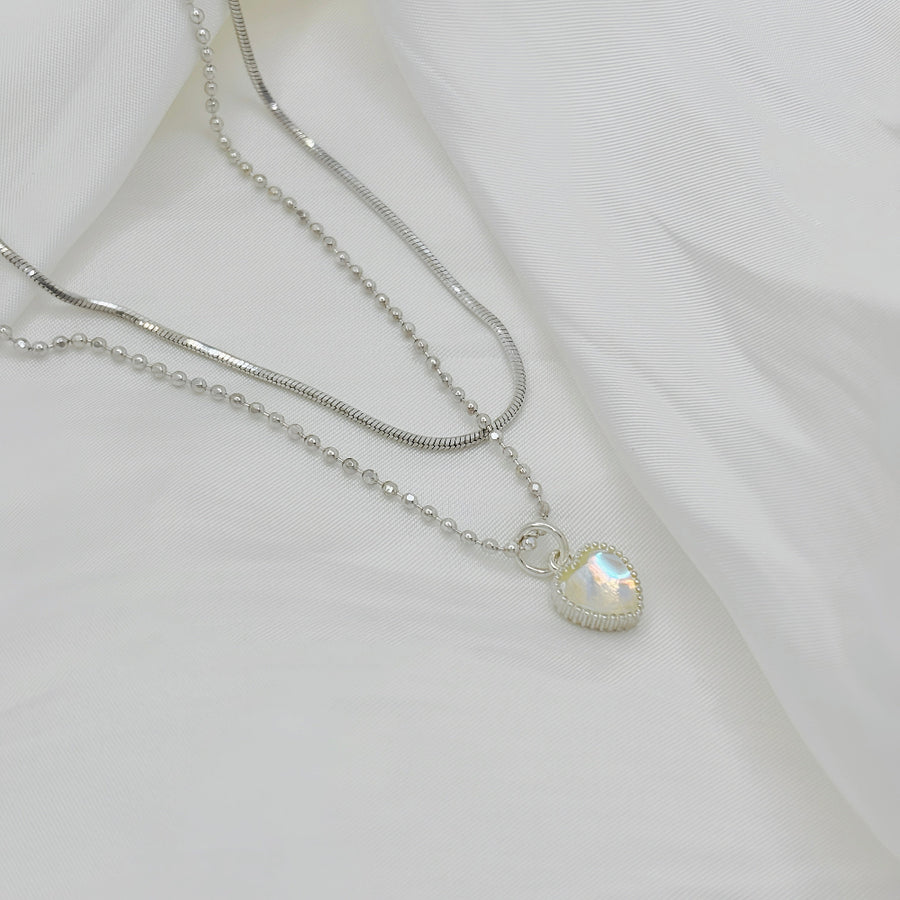 This silver necklace features a stunning moonstone heart-shaped pendant, radiating both beauty and kindness. Its unique design combines beaded and snake chain elements, creating a dual-layered chain for a visually striking effect that exudes a sense of fluidity.