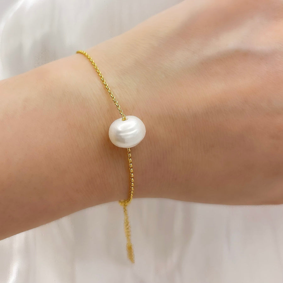 This elegant bracelet features a delicate gold chain adorned with a single, lustrous white pearl. The adjustable clasp ensures a perfect fit, making it a timeless and versatile accessory for any occasion. Crafted with high-quality materials and attention to detail, this bracelet adds a touch of sophistication and elegance to any outfit.