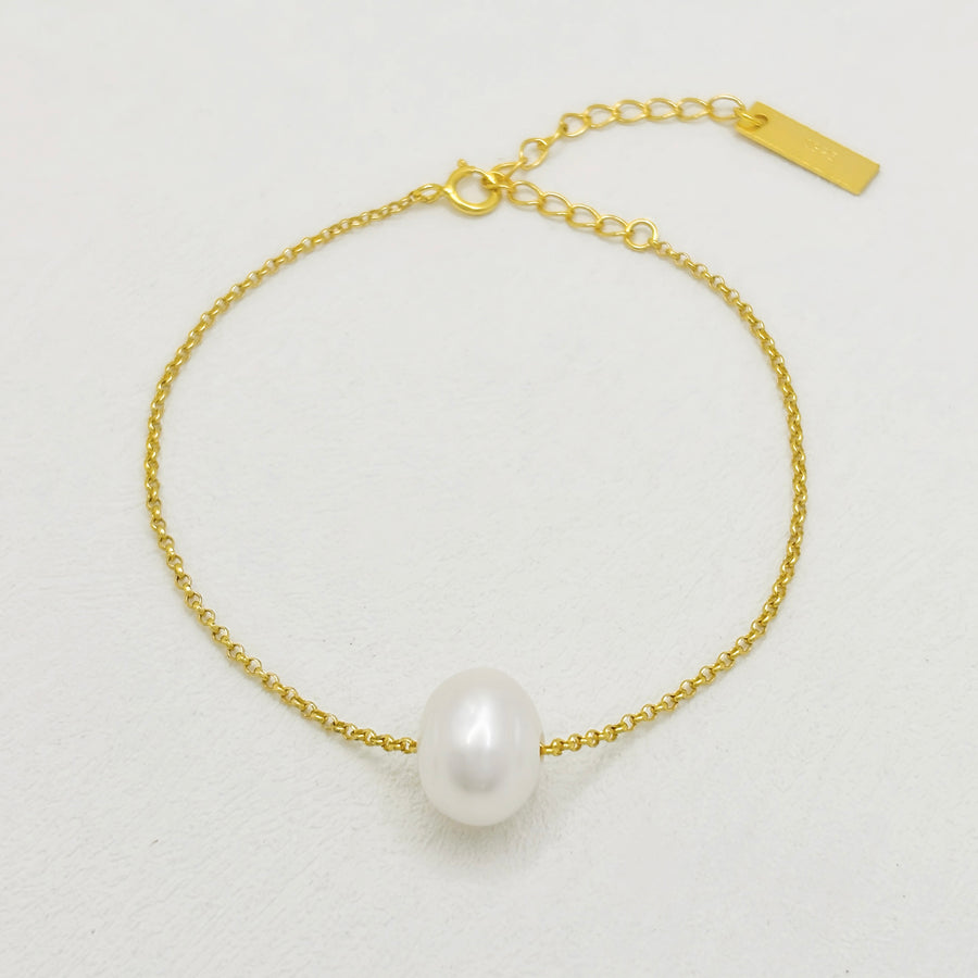 This elegant bracelet features a delicate gold chain adorned with a single, lustrous white pearl. The adjustable clasp ensures a perfect fit, making it a timeless and versatile accessory for any occasion. Crafted with high-quality materials and attention to detail, this bracelet adds a touch of sophistication and elegance to any outfit.