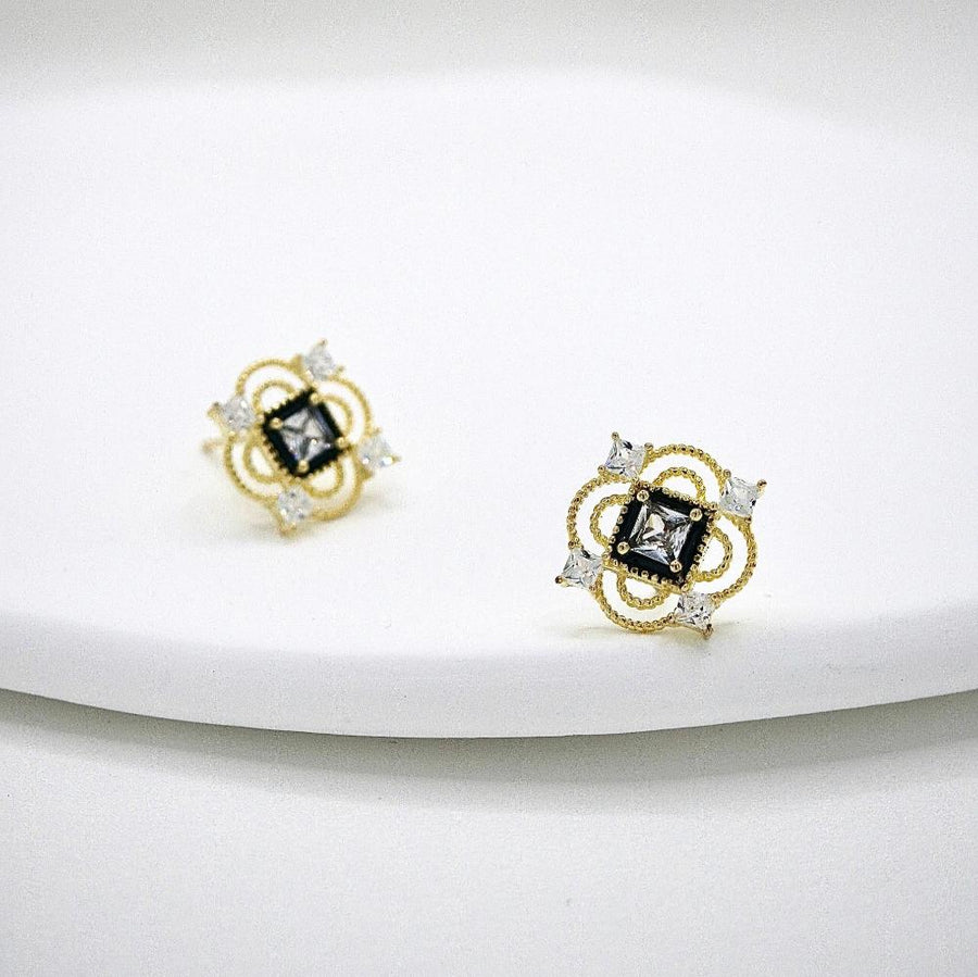 These vintage-inspired silver stud earrings feature a striking black square framed by intricate gold details and shimmering cubic zirconia accents. Perfect for adding a touch of glamour and sophistication to any outfit. 