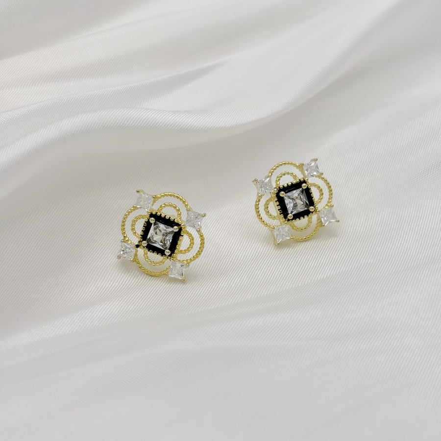 These vintage-inspired silver stud earrings feature a striking black square framed by intricate gold details and shimmering cubic zirconia accents. Perfect for adding a touch of glamour and sophistication to any outfit. 