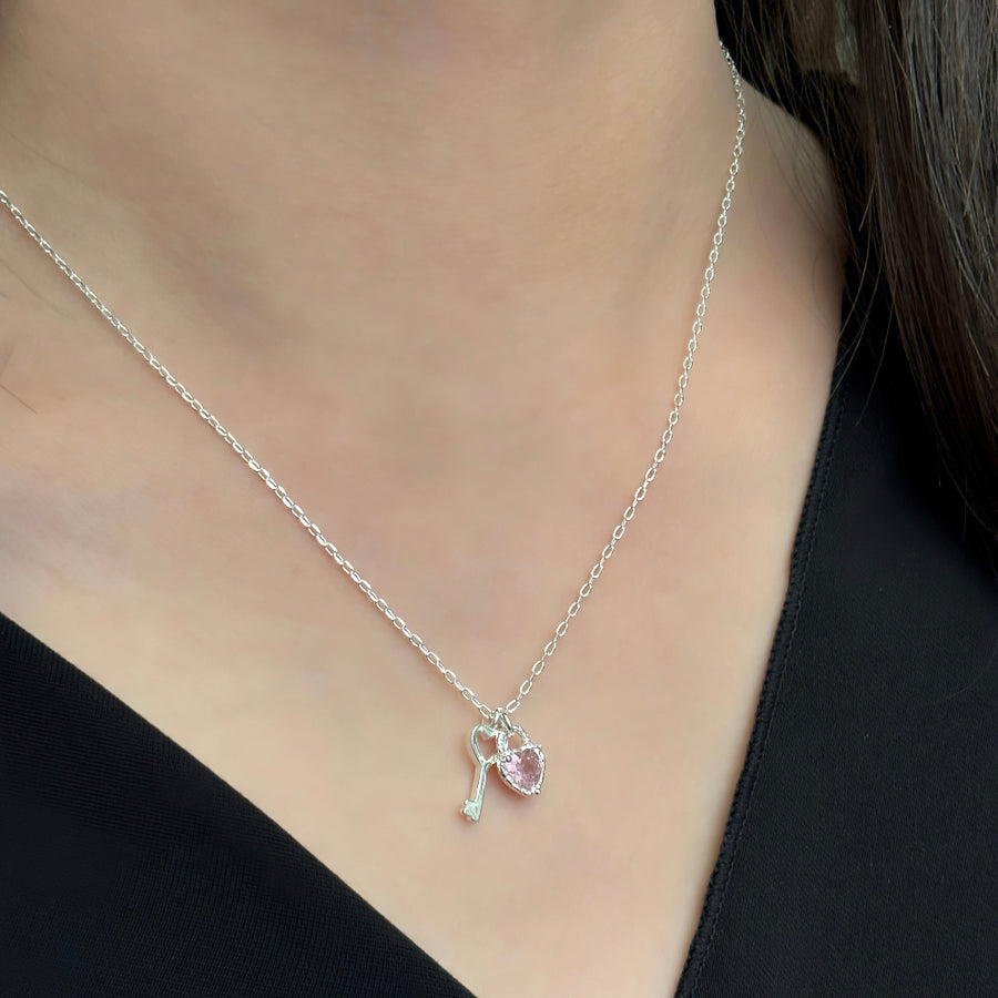 This 925 silver necklace features a stylish and enchanting design with dual pendants: a beautifully crafted pink cubic zirconia heart and a silver key. Its elegant and playful design makes it suitable for various occasions, exuding a sense of delicacy and charm. 