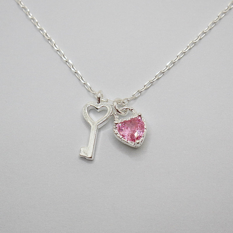 This 925 silver necklace features a stylish and enchanting design with dual pendants: a beautifully crafted pink cubic zirconia heart and a silver key. Its elegant and playful design makes it suitable for various occasions, exuding a sense of delicacy and charm. 