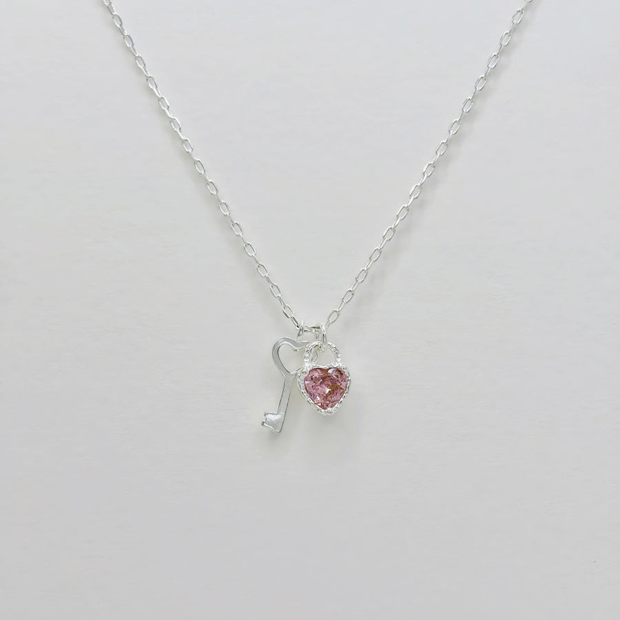 This 925 silver necklace features a stylish and enchanting design with dual pendants: a beautifully crafted pink cubic zirconia heart and a silver key. Its elegant and playful design makes it suitable for various occasions, exuding a sense of delicacy and charm. 