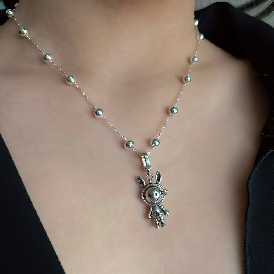 This necklace features a whimsical astronaut bunny with a double-sided, rotating face crafted from 925 sterling silver. With one side depicting a cheerful smile and the other showing a unhappy expression, it adds a playful and versatile touch to your jewelry collection. 