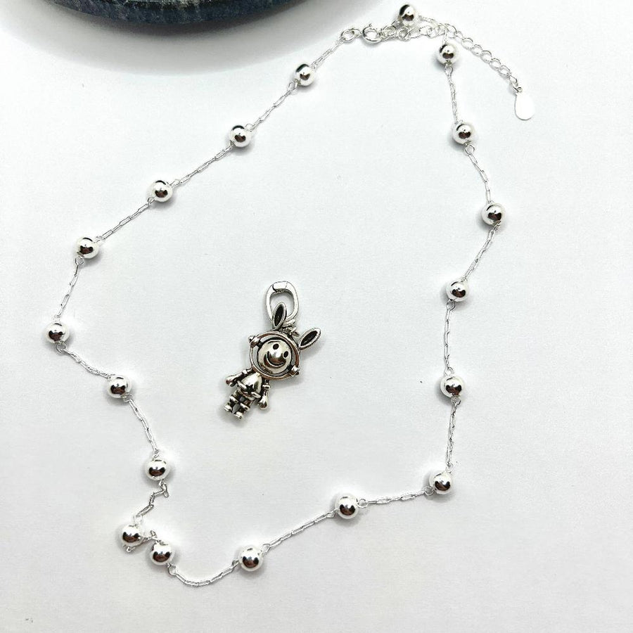 This necklace features a whimsical astronaut bunny with a double-sided, rotating face crafted from 925 sterling silver. With one side depicting a cheerful smile and the other showing a unhappy expression, it adds a playful and versatile touch to your jewelry collection. 