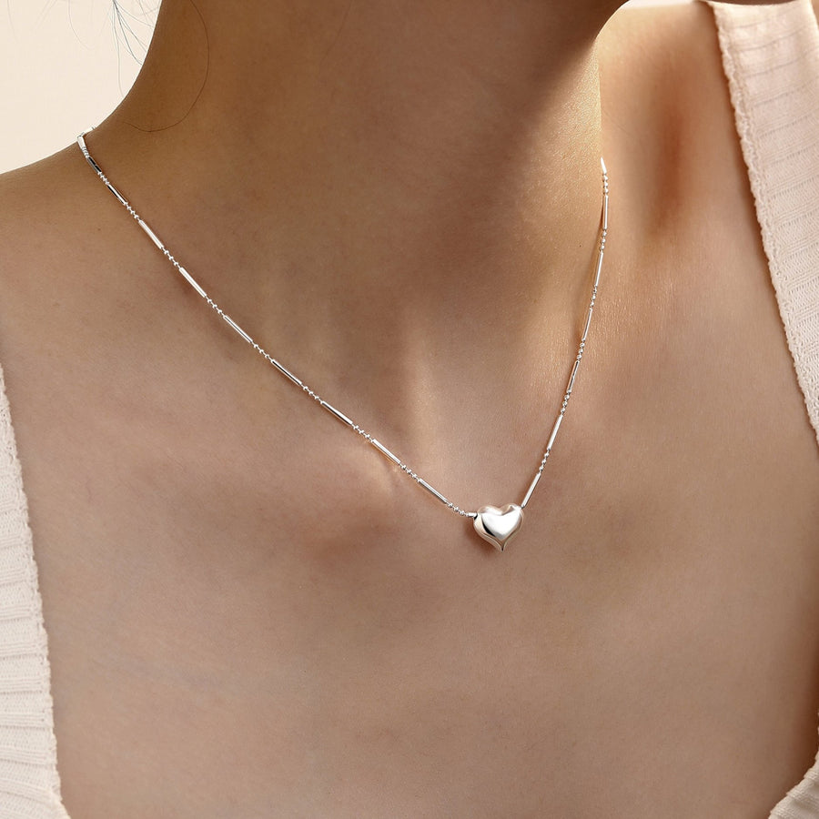 This 925 silver necklace features a puffy heart pendant in a sleek texture and high-shine polished finish. Paired with a delicate beaded chain, this necklace combines subtle texture with sophisticated charm.