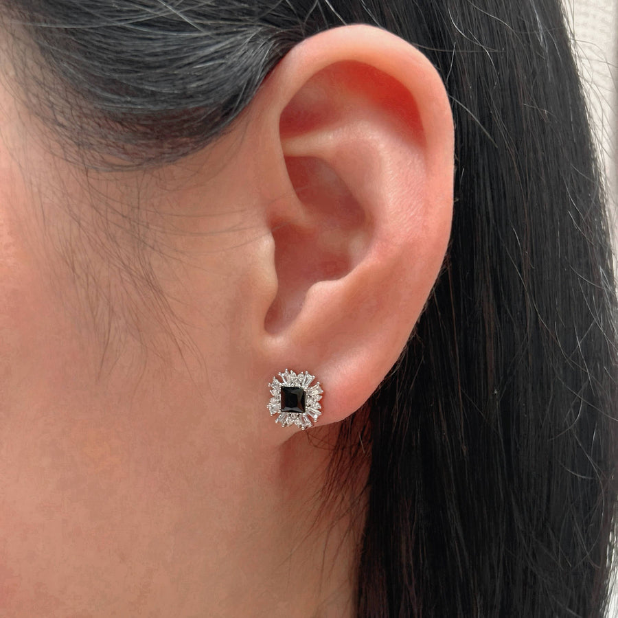 These stunning black cubic zirconia silver stud earrings are surrounded by a burst of shimmering cubic zirconia, creating a striking starburst design.