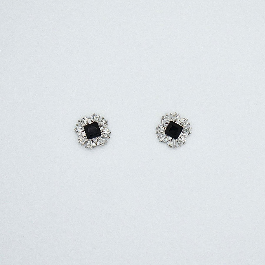 These stunning black cubic zirconia silver stud earrings are surrounded by a burst of shimmering cubic zirconia, creating a striking starburst design.