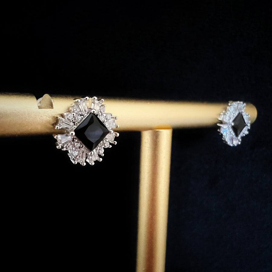 These stunning black cubic zirconia silver stud earrings are surrounded by a burst of shimmering cubic zirconia, creating a striking starburst design.