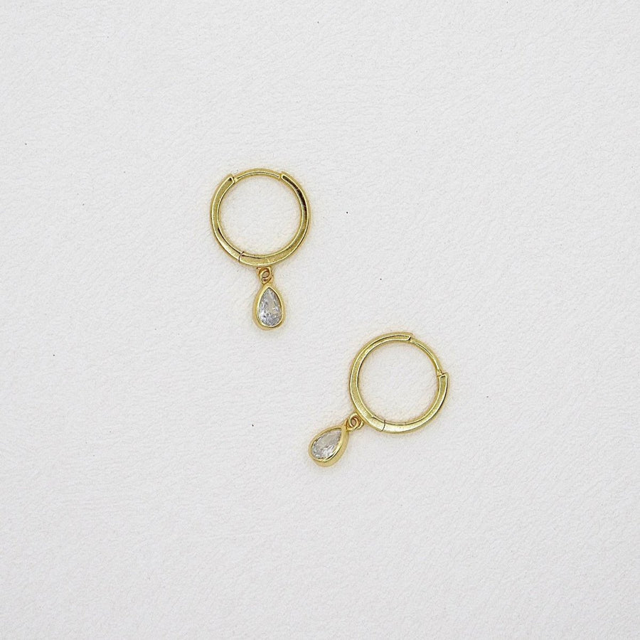 These elegant gold hoop earrings feature a delicate teardrop-shaped cubic zircon pendant, adding a touch of sophistication and sparkle to any outfit. Perfect for both casual and formal occasions, these earrings are a timeless addition to any jewelry collection.