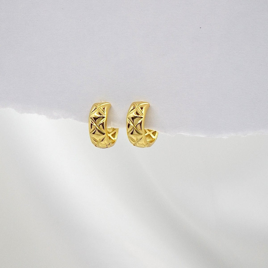 These elegant gold hoop earrings feature a unique geometric pattern, adding a touch of sophistication to any outfit. Perfect for both casual and formal occasions, these earrings are a must-have accessory for any jewelry collection.