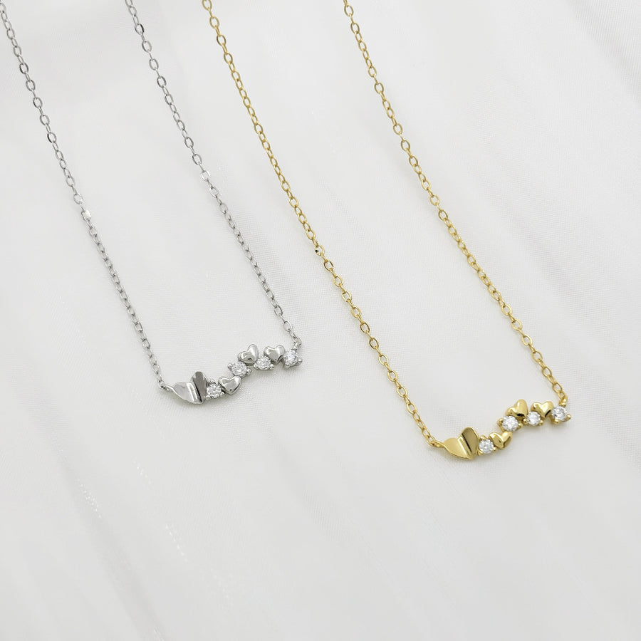 This elegant necklace features a delicate gold chain adorned with a series of small gold hearts interspersed with sparkling cubic zircon. The design is both charming and sophisticated, making it a perfect accessory for any occasion. 