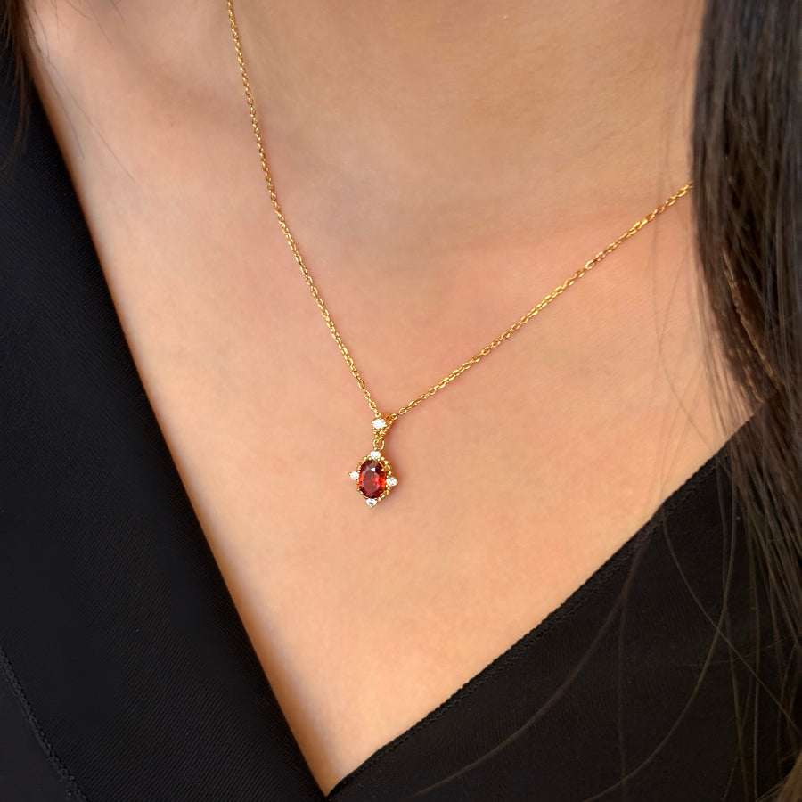 This elegant necklace features a stunning red cubic zircon set in a delicate gold chain. The central gemstone is surrounded by small, sparkling cubic zircon, adding a touch of sophistication and brilliance to the piece. Perfect for special occasions or everyday wear, this necklace combines timeless elegance with modern charm.