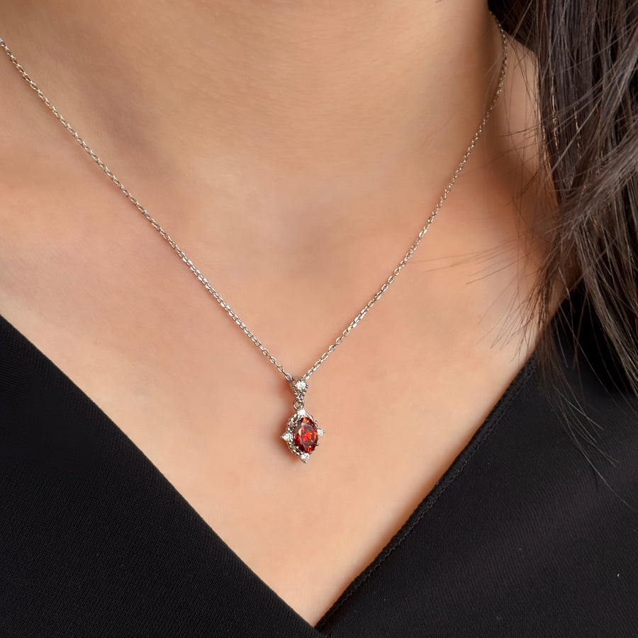 This elegant necklace features a stunning red cubic zircon set in a delicate silver chain. The central gemstone is surrounded by small, sparkling cubic zircon, adding a touch of sophistication and brilliance to the piece. Perfect for special occasions or everyday wear, this necklace combines timeless elegance with modern charm.