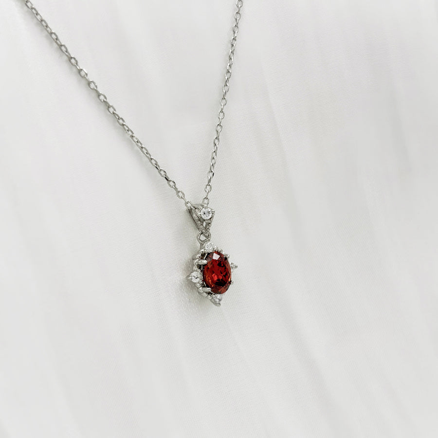 This elegant necklace features a stunning red cubic zircon set in a delicate silver chain. The central gemstone is surrounded by small, sparkling cubic zircon, adding a touch of sophistication and brilliance to the piece. Perfect for special occasions or everyday wear, this necklace combines timeless elegance with modern charm.