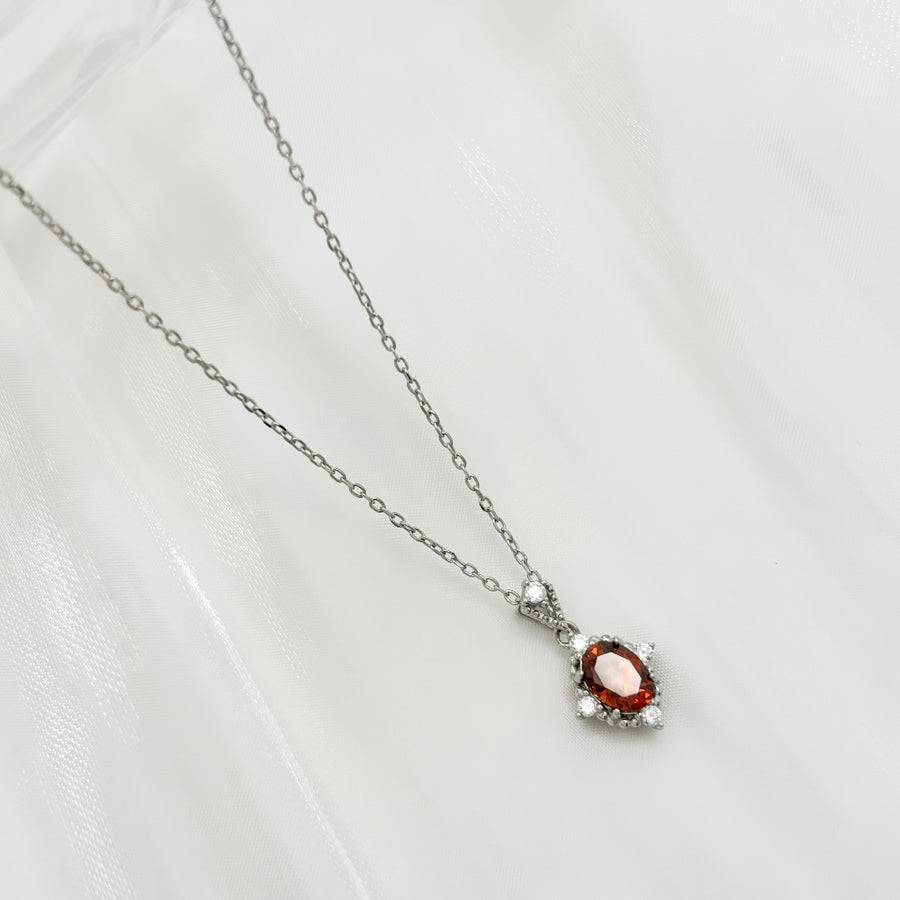 This elegant necklace features a stunning red cubic zircon set in a delicate silver chain. The central gemstone is surrounded by small, sparkling cubic zircon, adding a touch of sophistication and brilliance to the piece. Perfect for special occasions or everyday wear, this necklace combines timeless elegance with modern charm.