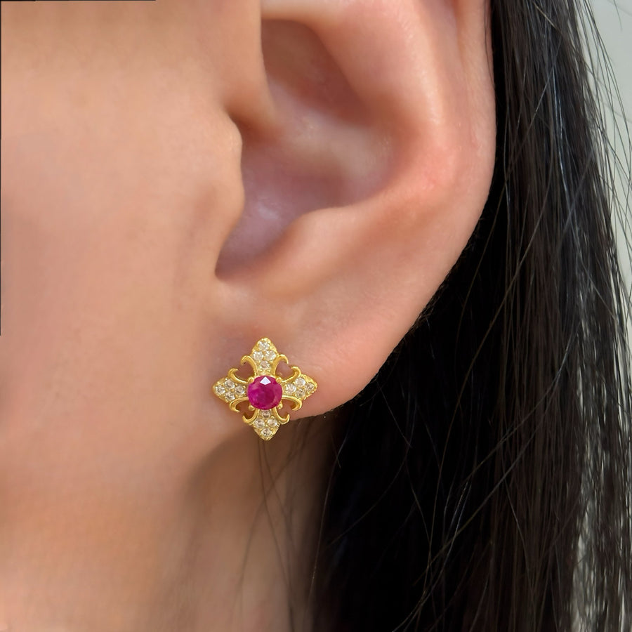 These exquisite earrings feature a central round ruby cubic zircon, surrounded by a delicate gold floral design. The petals are adorned with sparkling cubic zircon, creating a luxurious and elegant look. Perfect for special occasions or adding a touch of elegance to your everyday style, these earrings are a timeless addition to any jewelry collection. 